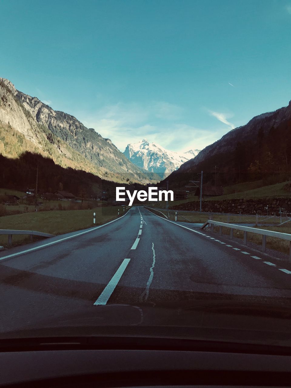 Road amidst mountains seen through car windshield