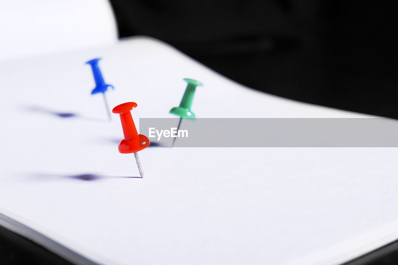 Close-up of colorful thumbtacks on blank paper