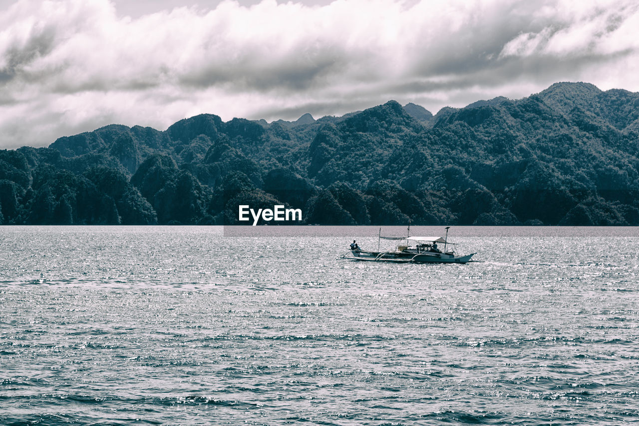 NAUTICAL VESSEL SAILING ON SEA AGAINST MOUNTAINS