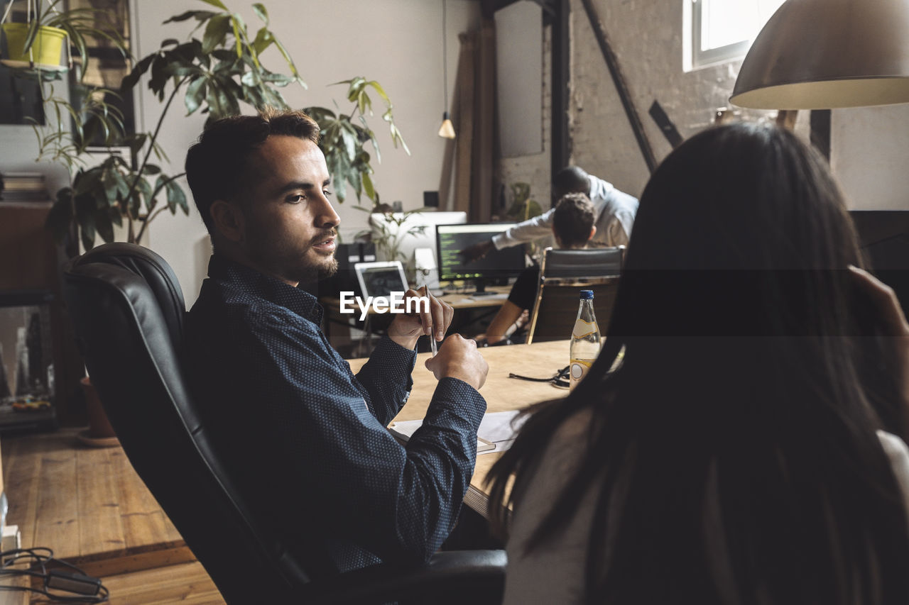 Entrepreneur talking to female colleague at workplace