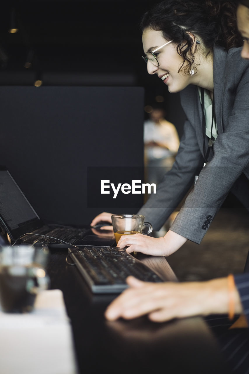 Smiling it professionals working by coworker on laptop in office