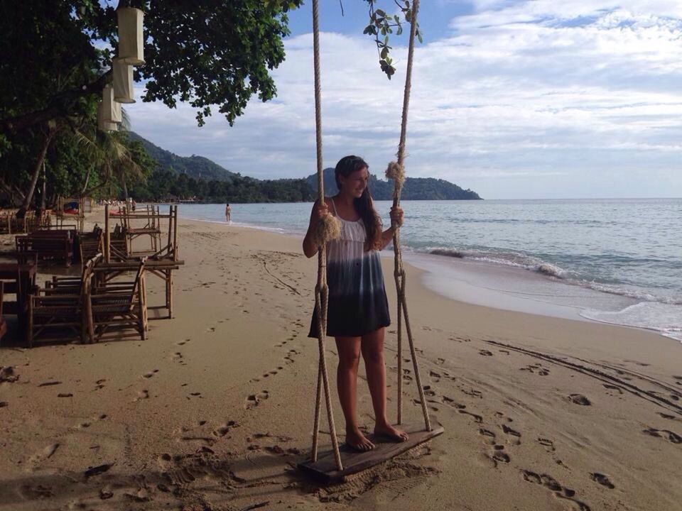 Woman standing on swing at beach by sea