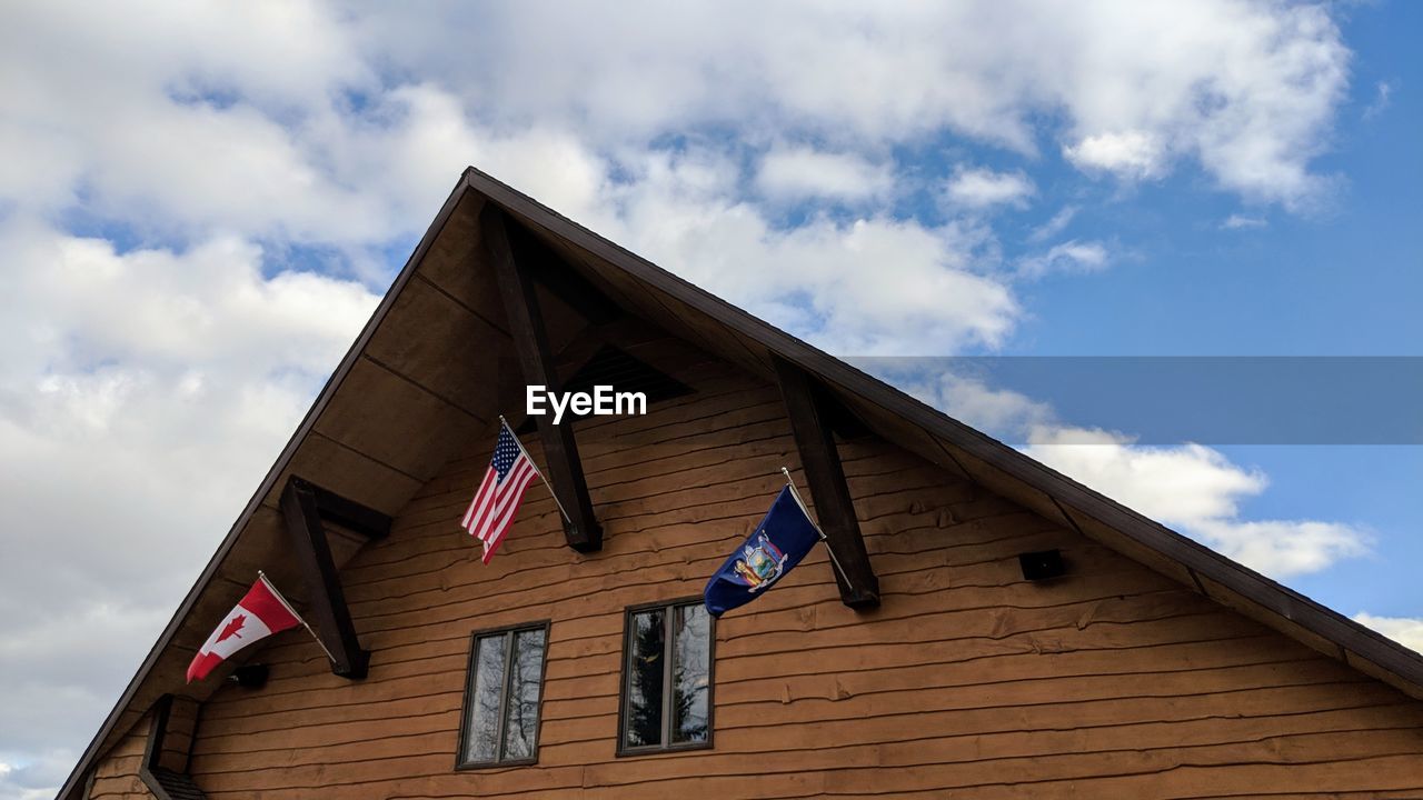 LOW ANGLE VIEW OF FLAGS ON HOUSE AGAINST SKY