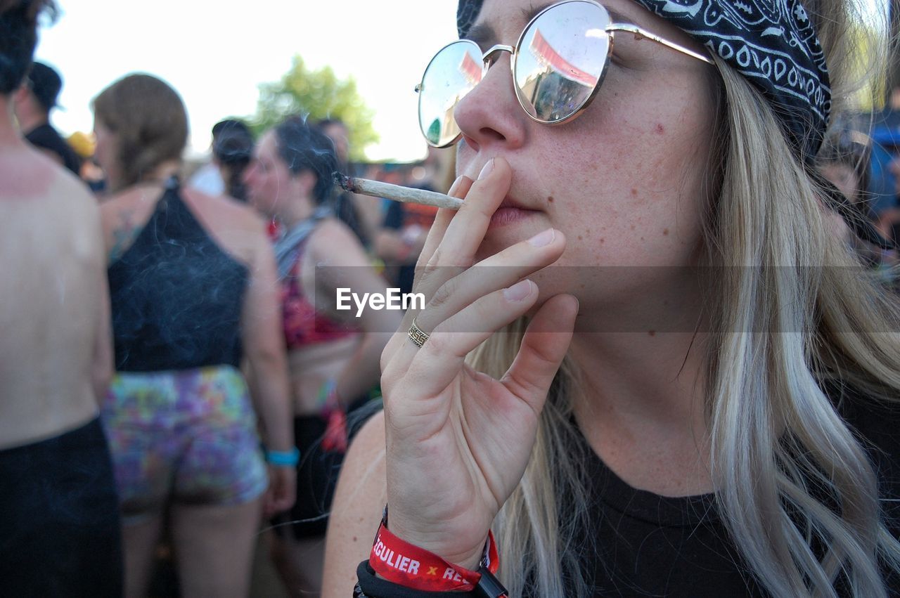 CLOSE-UP PORTRAIT OF WOMAN HOLDING SUNGLASSES