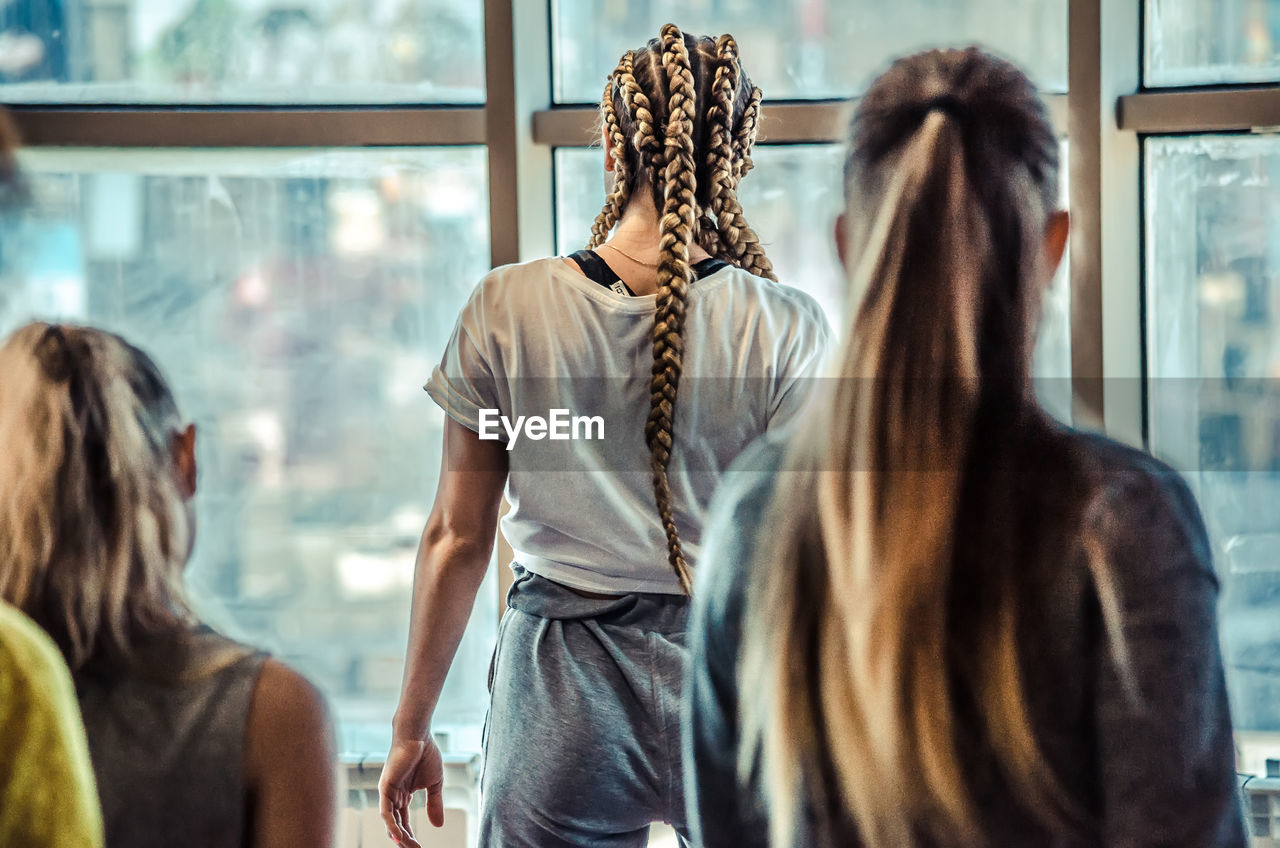 Rear view of women standing against window