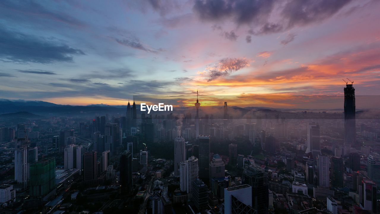 Aerial view of city against cloudy sky during sunset