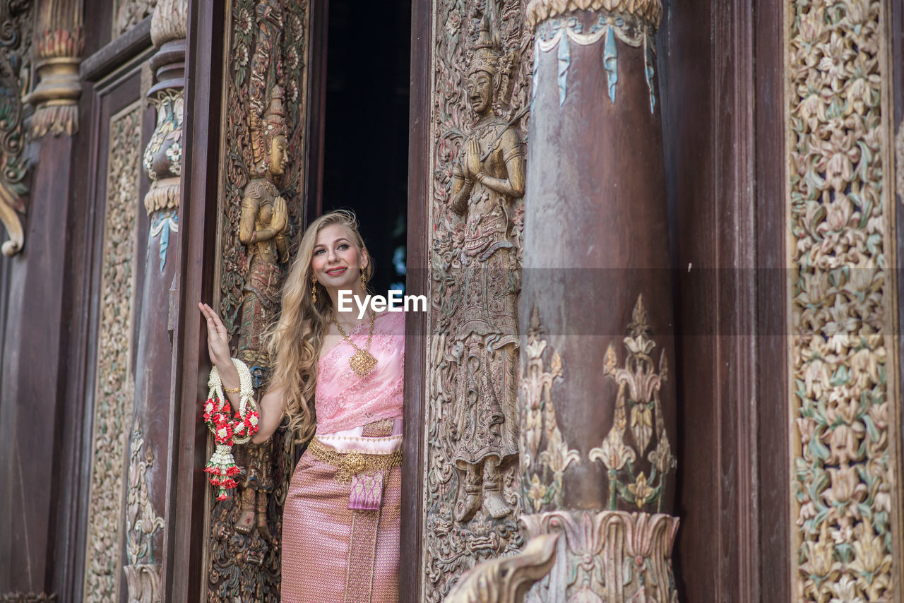 Portrait of woman standing by historical built structure