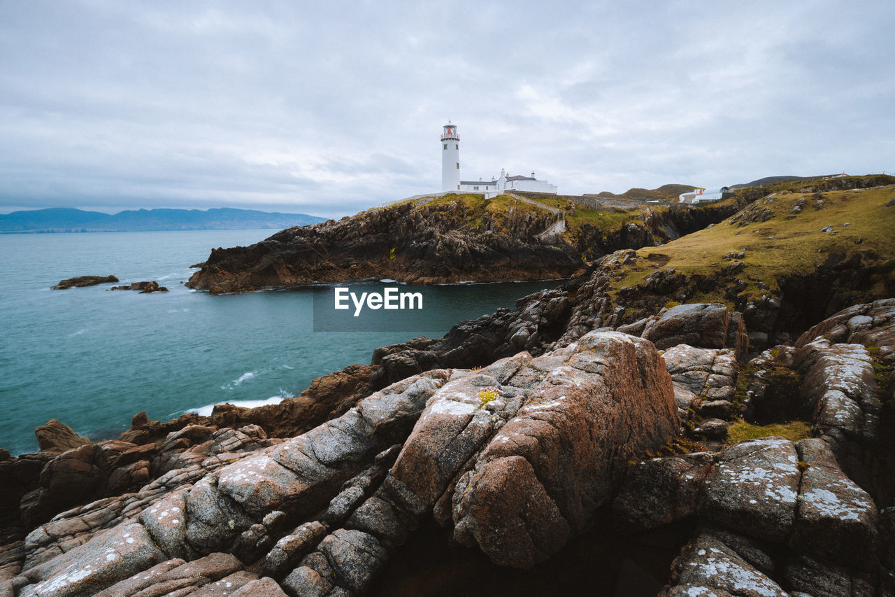 Lighthouse by sea against sky