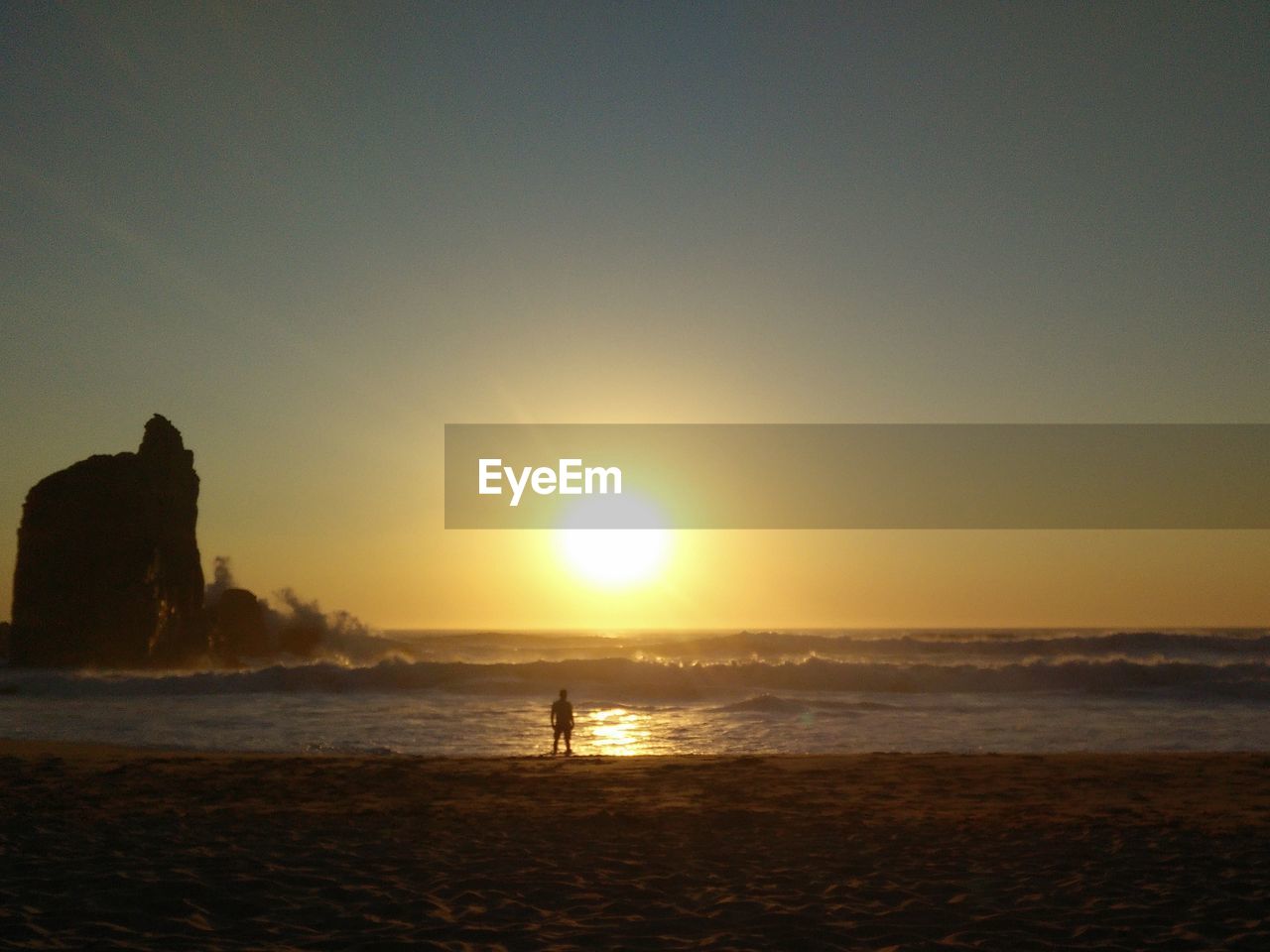 Silhouette person on beach against sky during sunset