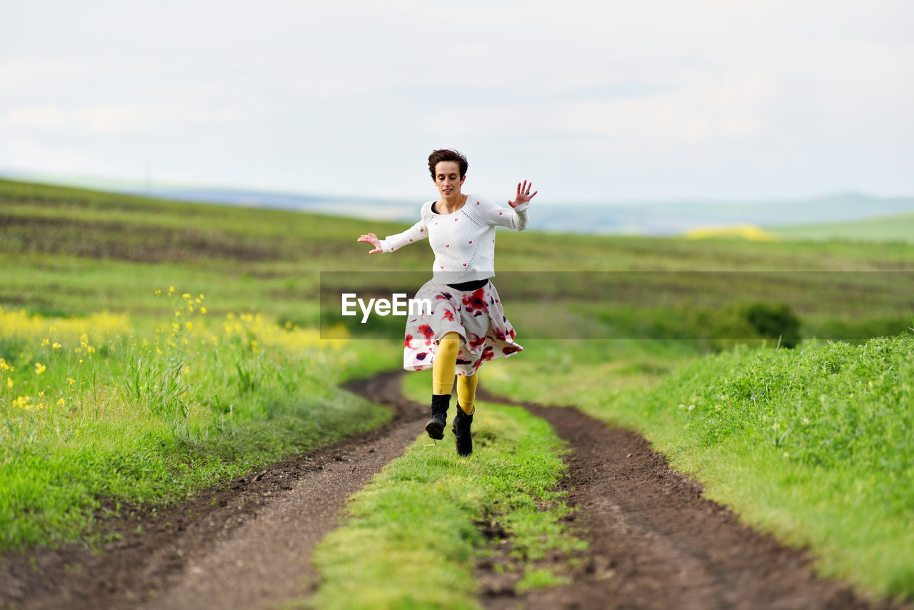 Young man running on field against sky