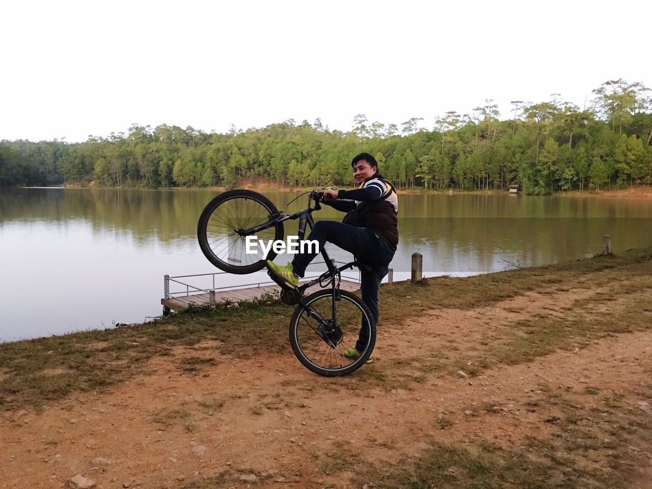 WOMAN ON BICYCLE BY LAKE