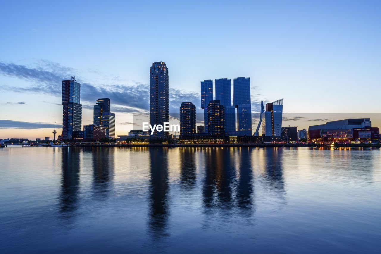 River by modern buildings against sky in city