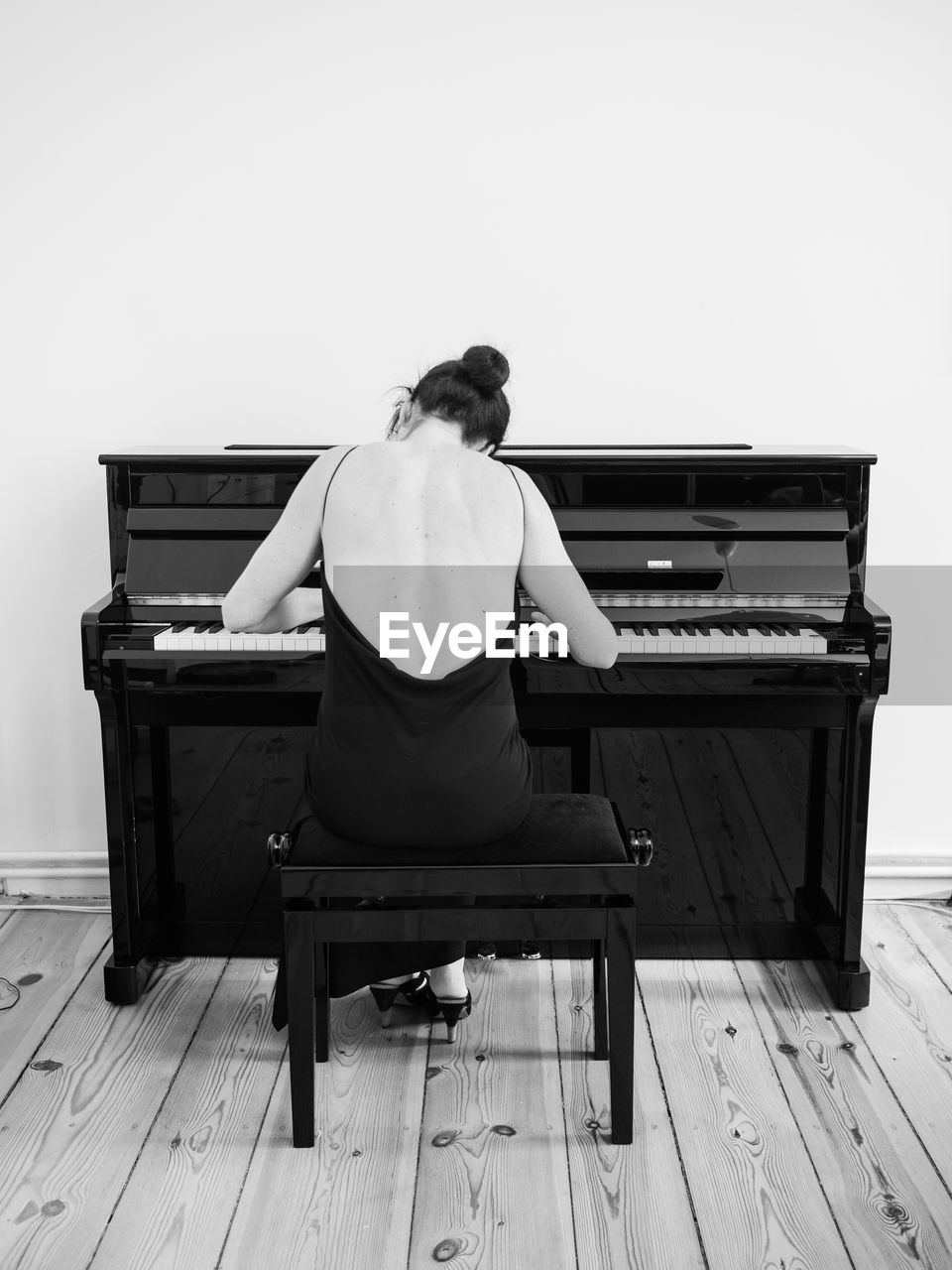 REAR VIEW OF MAN PLAYING PIANO AGAINST CLEAR SKY AT HOME