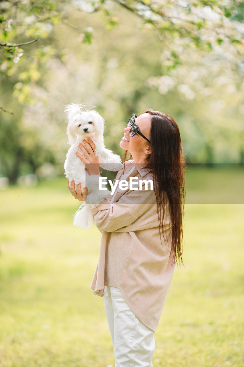 Side view of woman with dog standing park