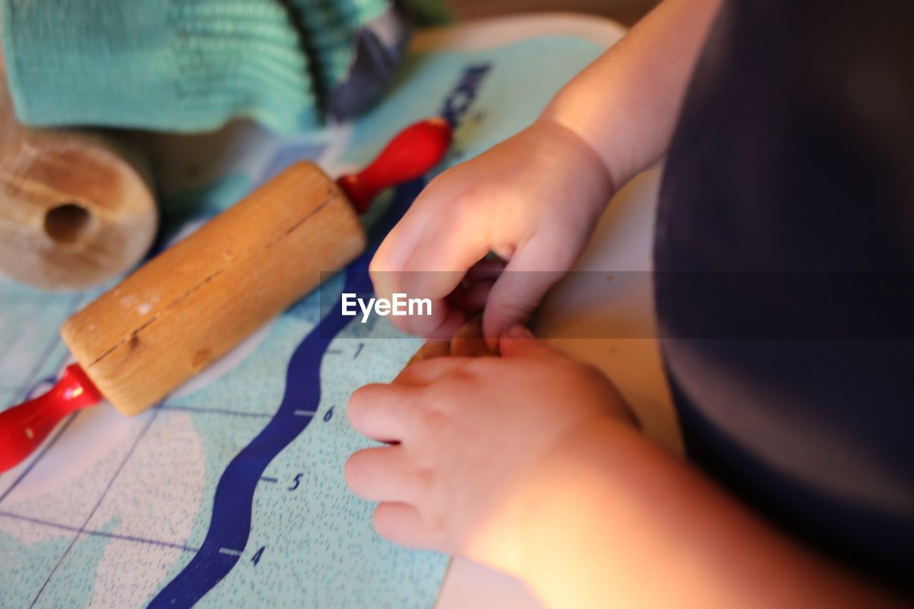 Cropped image of child preparing gingerbread cookie at table