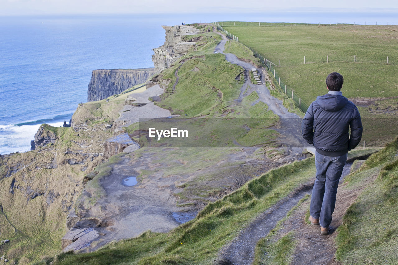 Rear view of man walking on cliffs of moher