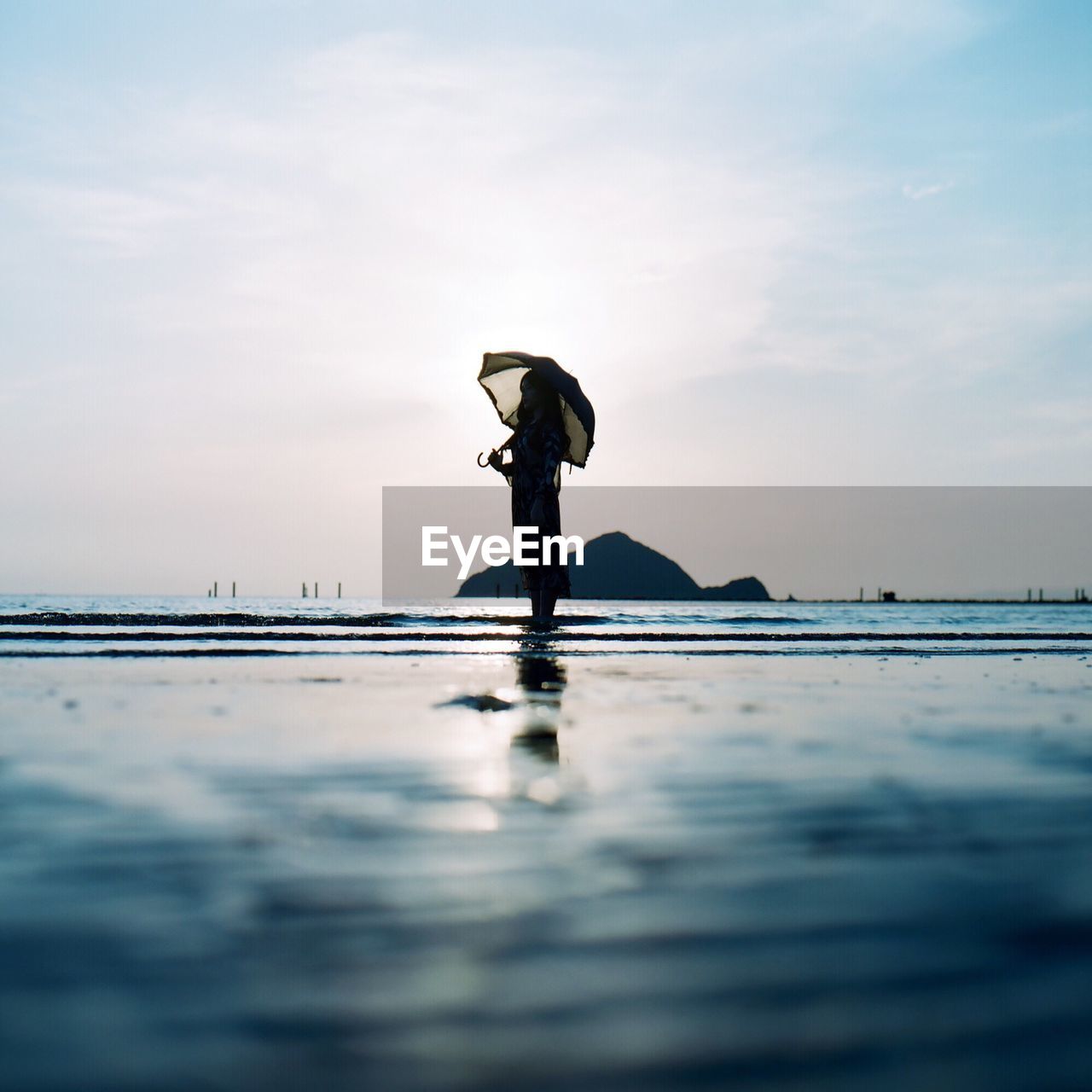 Woman standing in sea against sky on sunny day