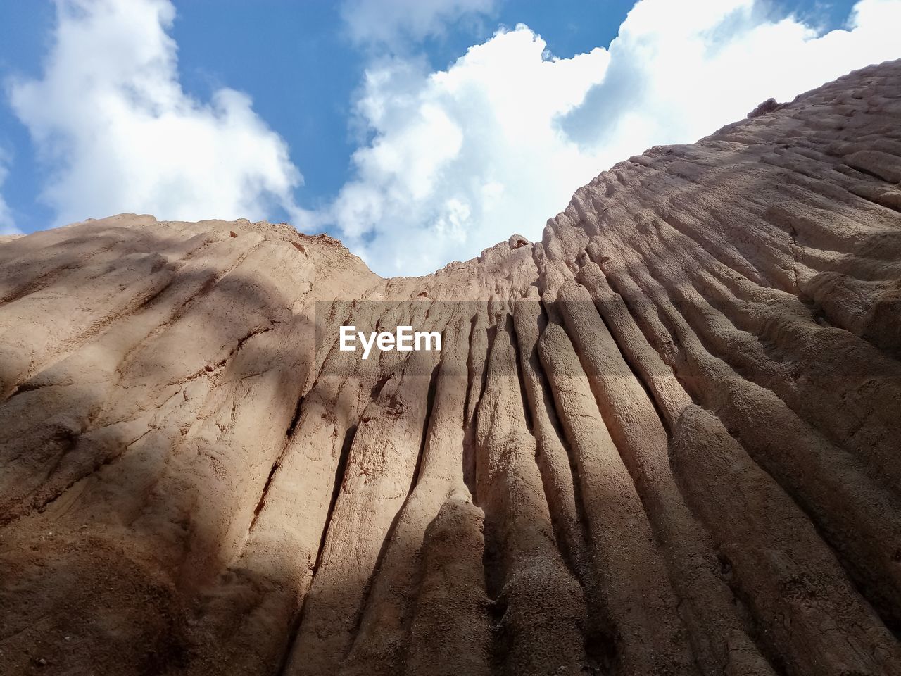 Low angle view of rock formations against cloudy sky