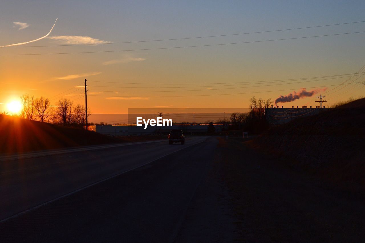 CAR ON ROAD AGAINST SKY DURING SUNSET