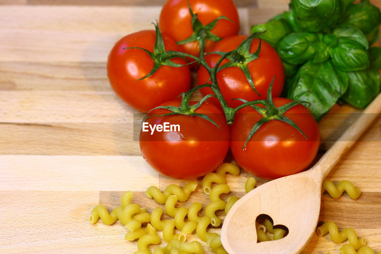 Tomatoes noodels and vegetables on cutting board with wooden spoon 