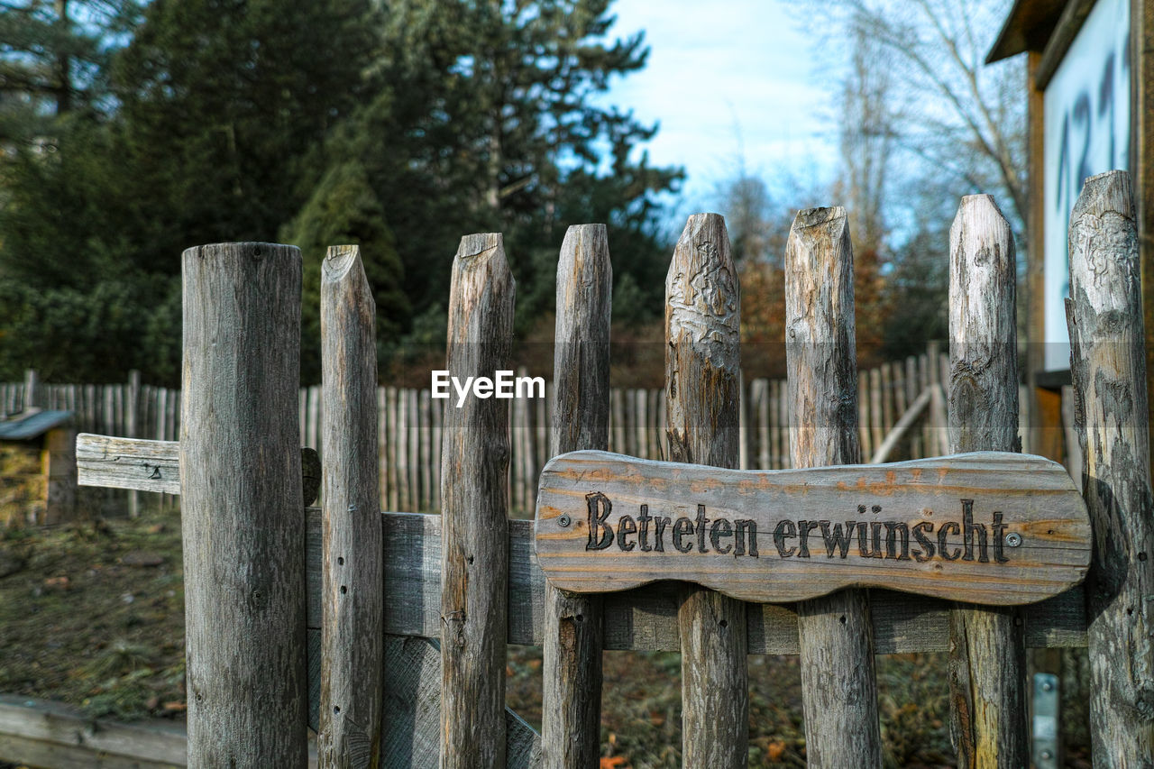 TEXT ON WOODEN POST AGAINST FENCE