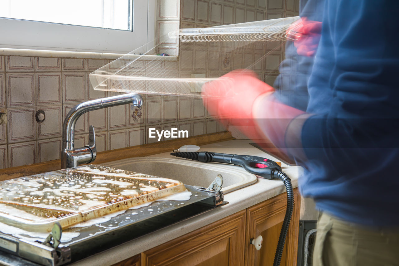 Cleaning the oven. man's hand in household cleaning gloves cleans oven inside.