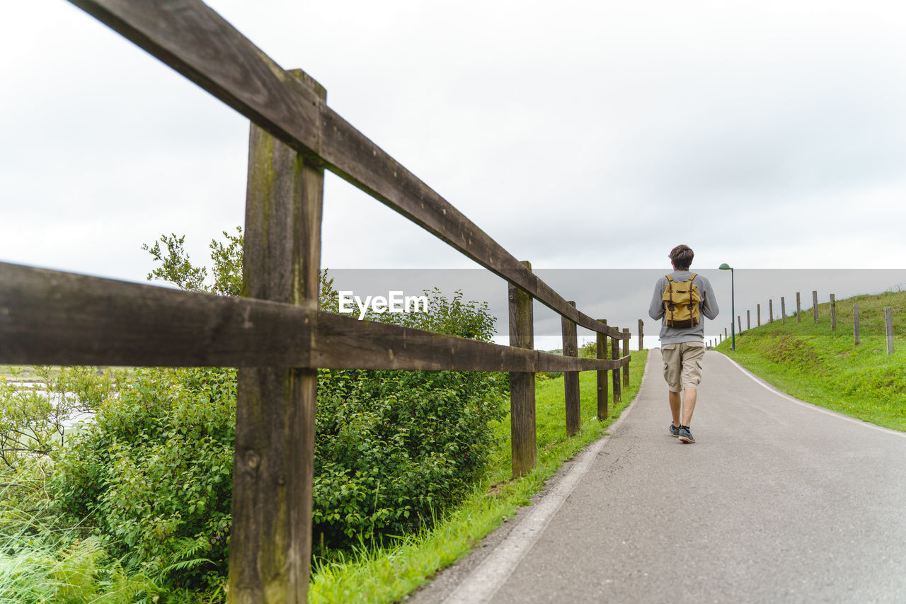 rear view of man walking on road against clear sky