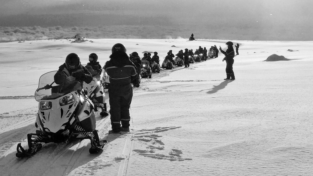 View of people riding snowmobile on snow covered landscape