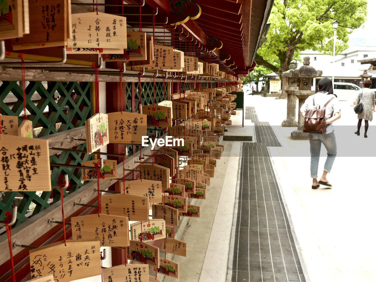 Full length rear view of women walking by messages hanging from temple