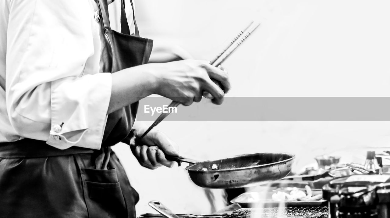 SIDE VIEW OF MAN PREPARING FOOD ON BARBECUE