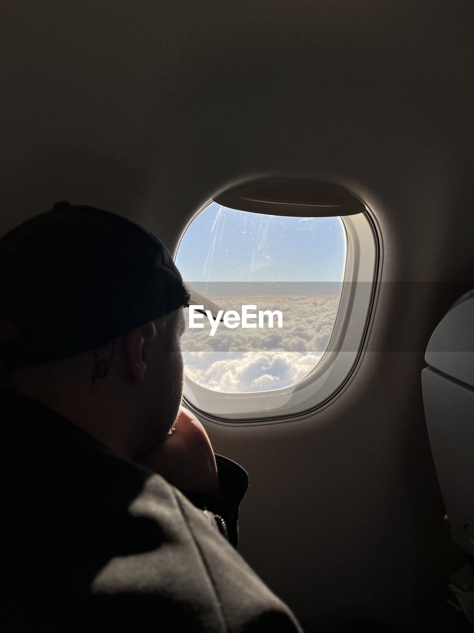 cropped hand of man looking through airplane window