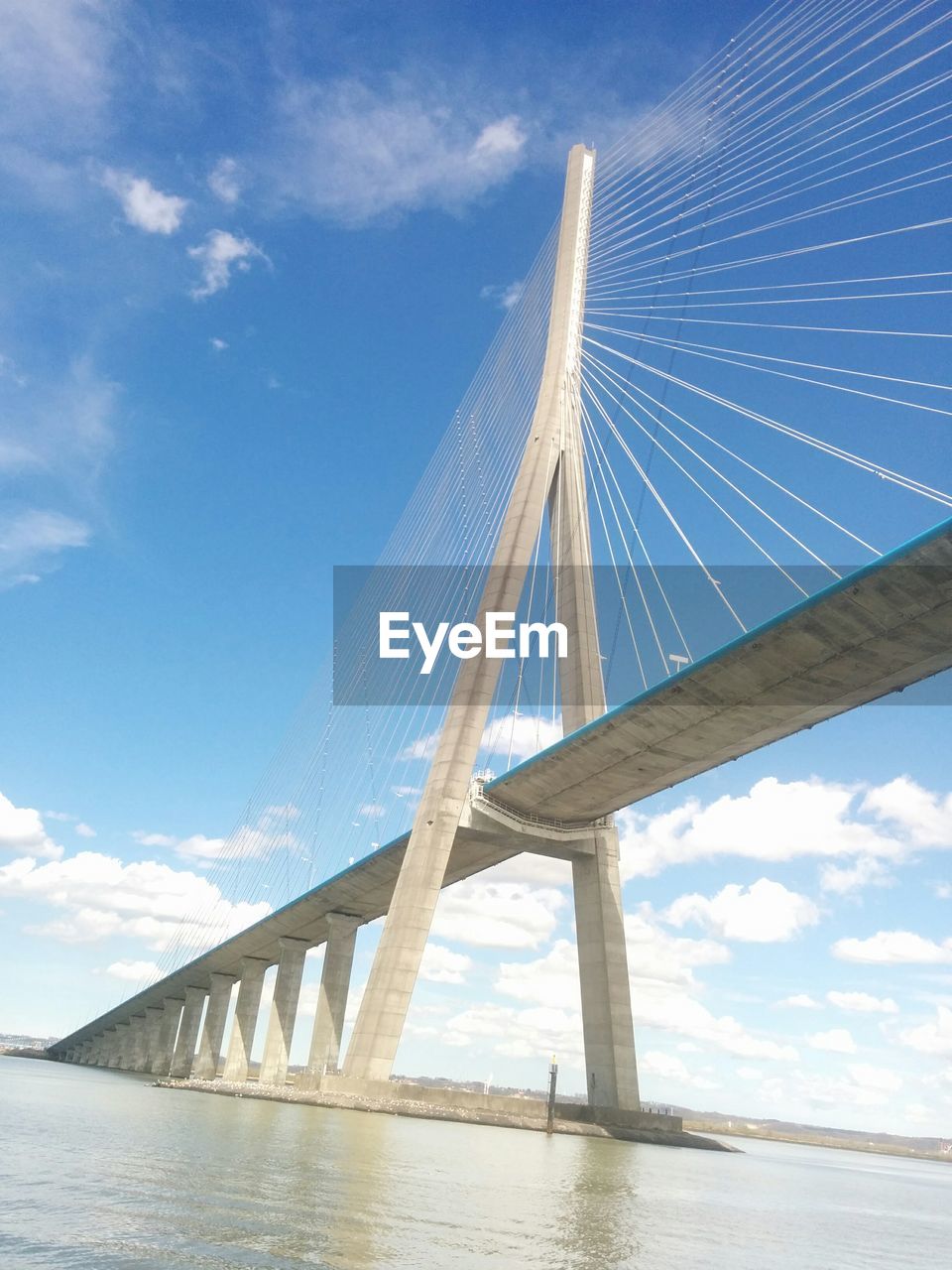 Low angle view of bridge over water against blue sky