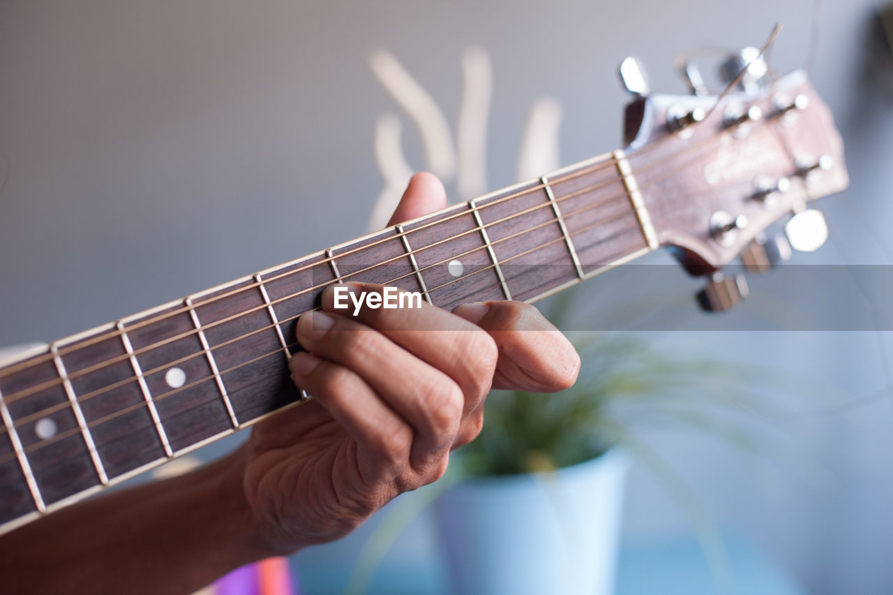 Cropped hand playing guitar at home