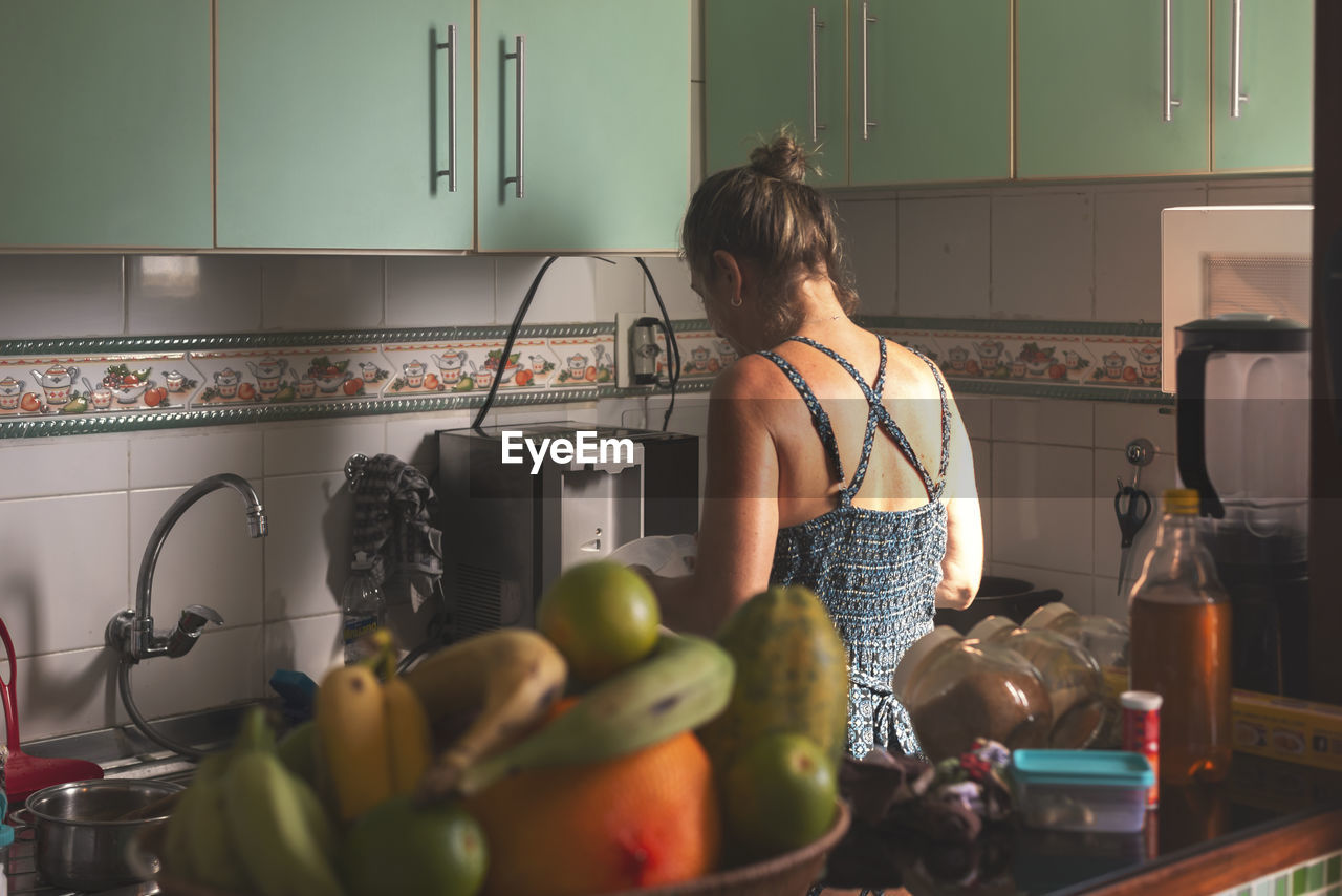 Caucasian woman with her back to her cooking in the kitchen. 