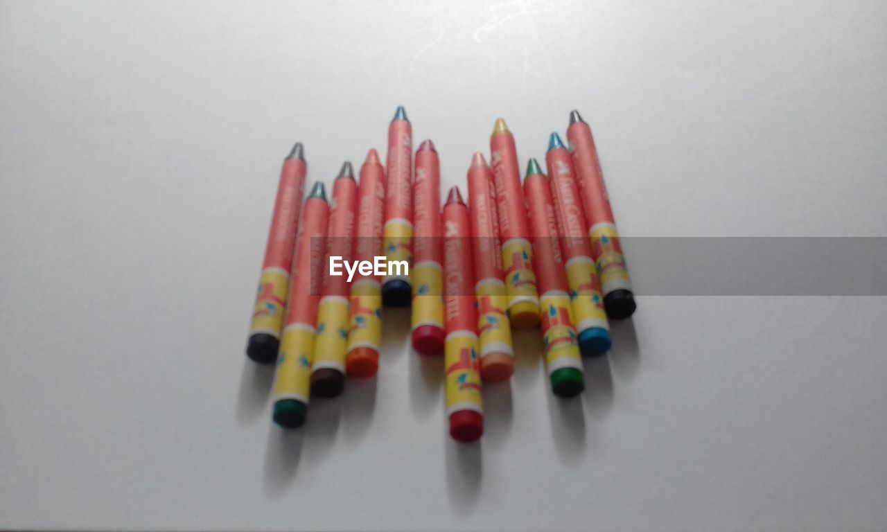 CLOSE-UP OF MULTI COLORED PENCILS AGAINST WHITE BACKGROUND