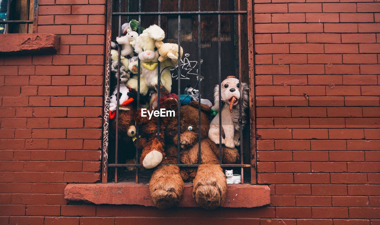 Stuffed toys in window of brick wall