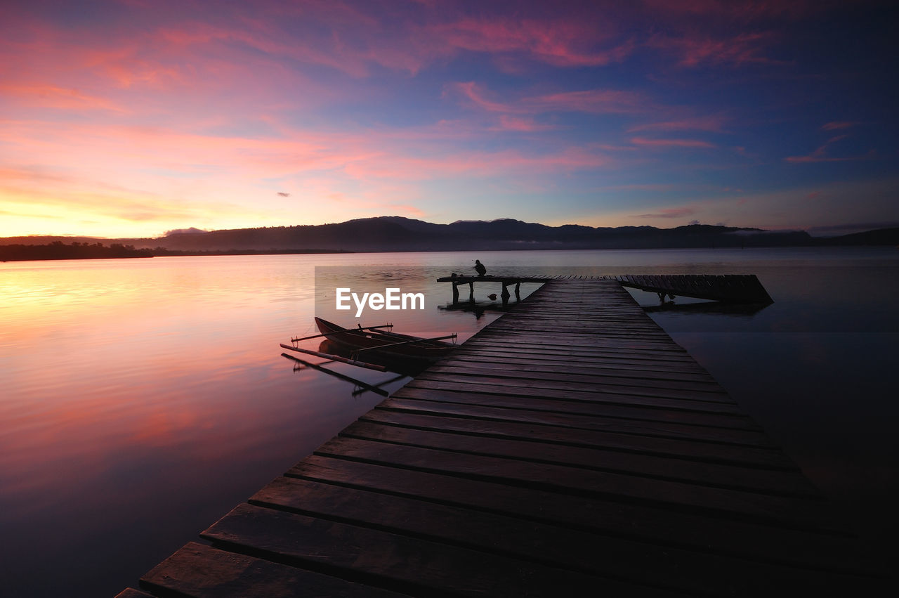 Pier over lake against sky during sunset