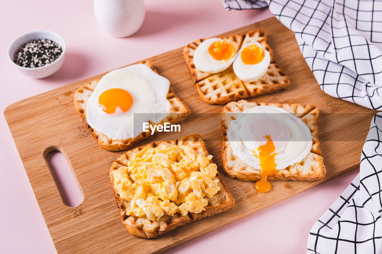 Eggs prepared to different recipes on toast on a wooden board