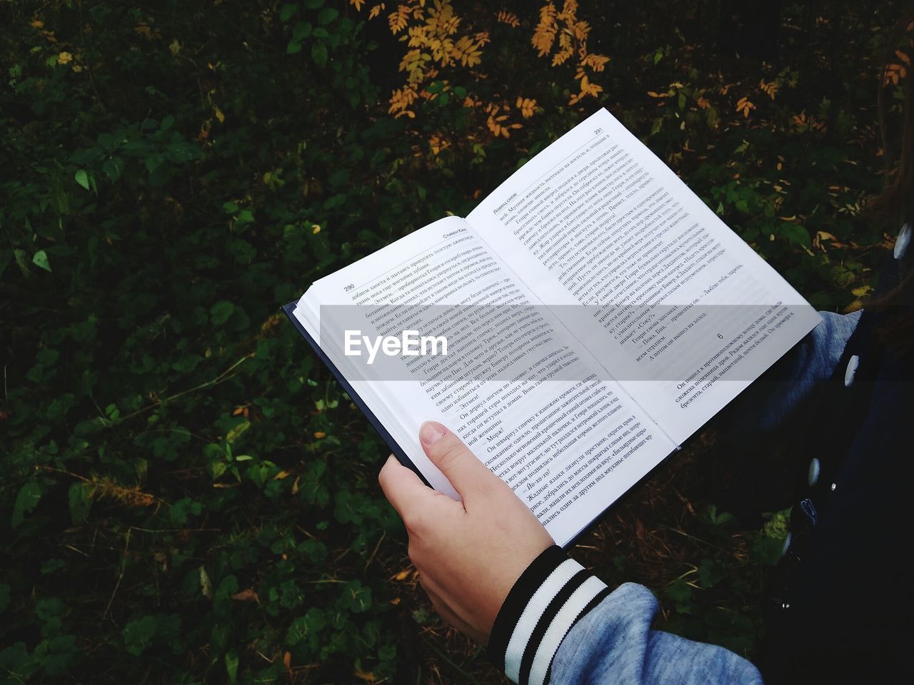 Midsection of person holding book on field