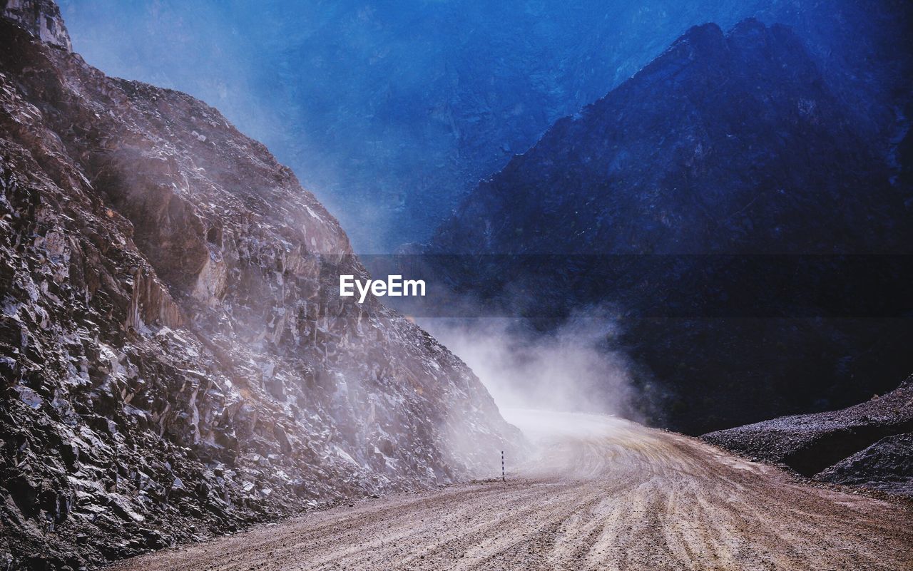 Dust over dirt road amidst rocky mountains