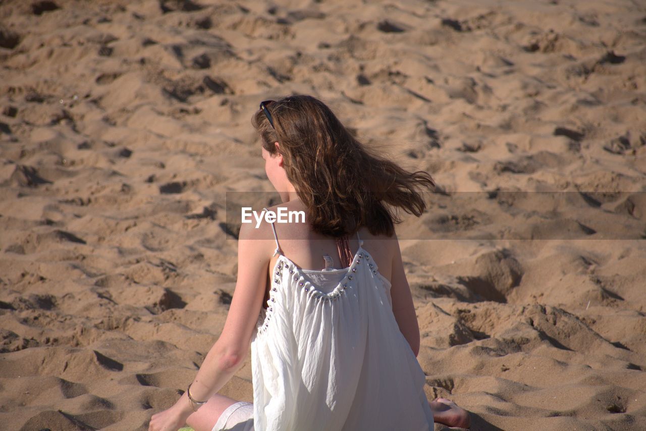 Rear view of woman sitting on beach