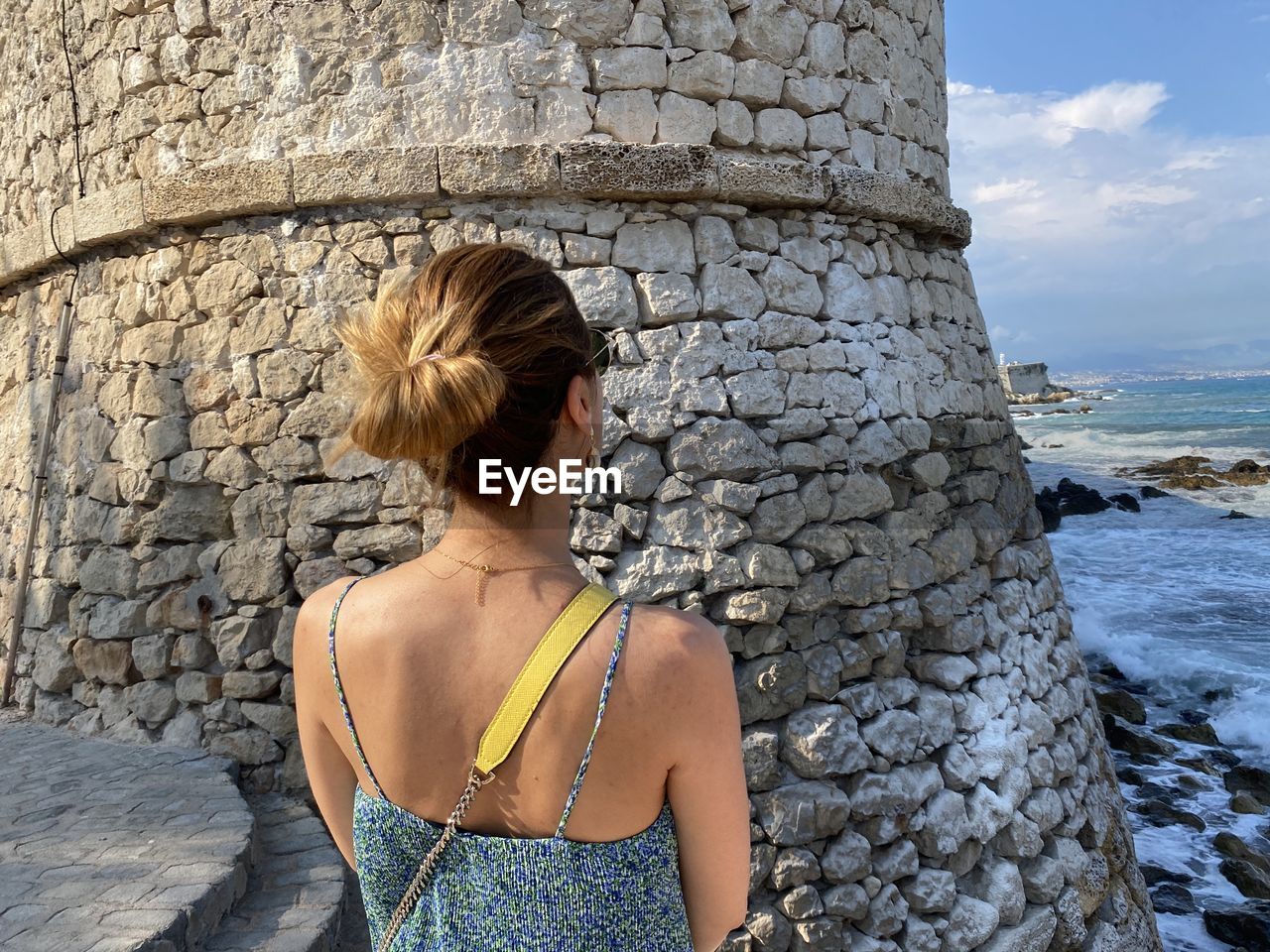 REAR VIEW OF WOMAN STANDING AGAINST SEA