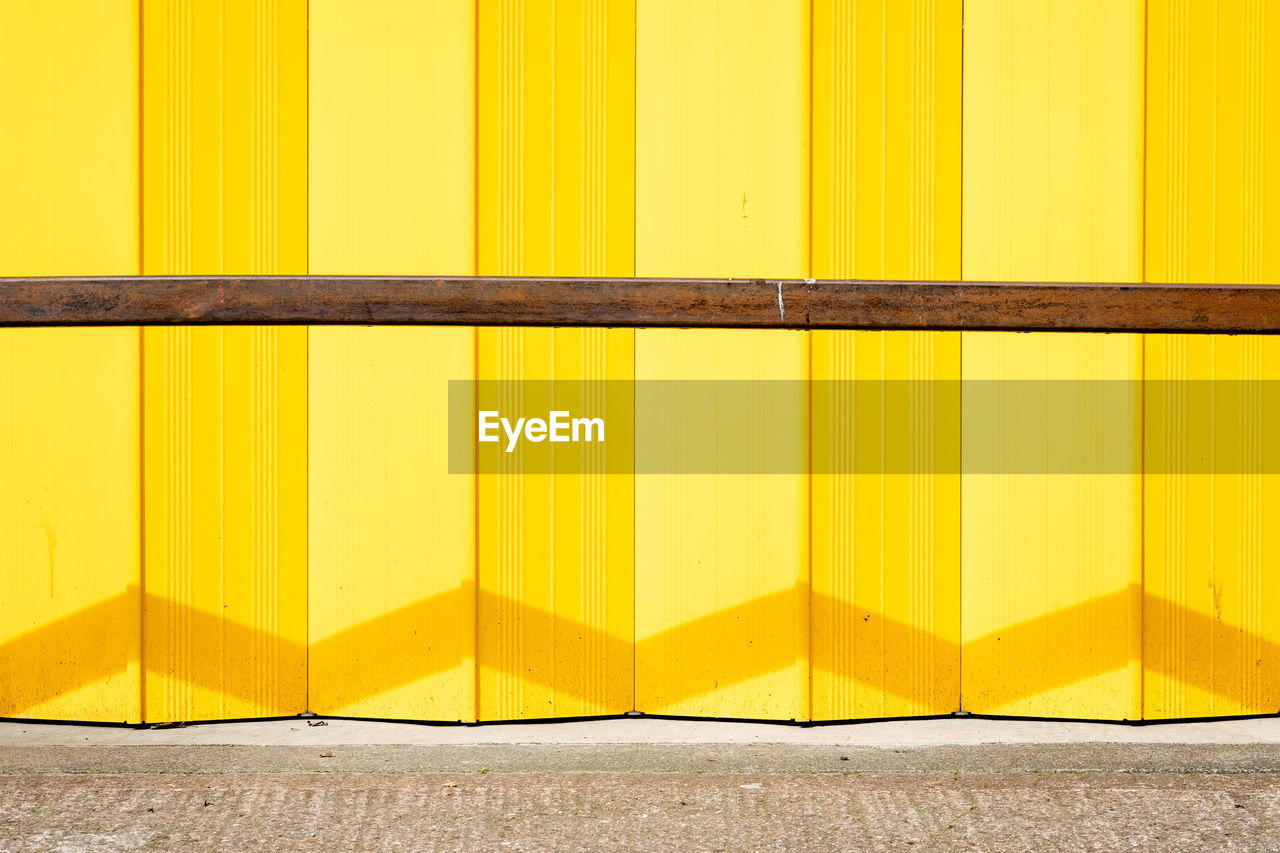 FULL FRAME SHOT OF YELLOW WALL WITH FOOTPATH