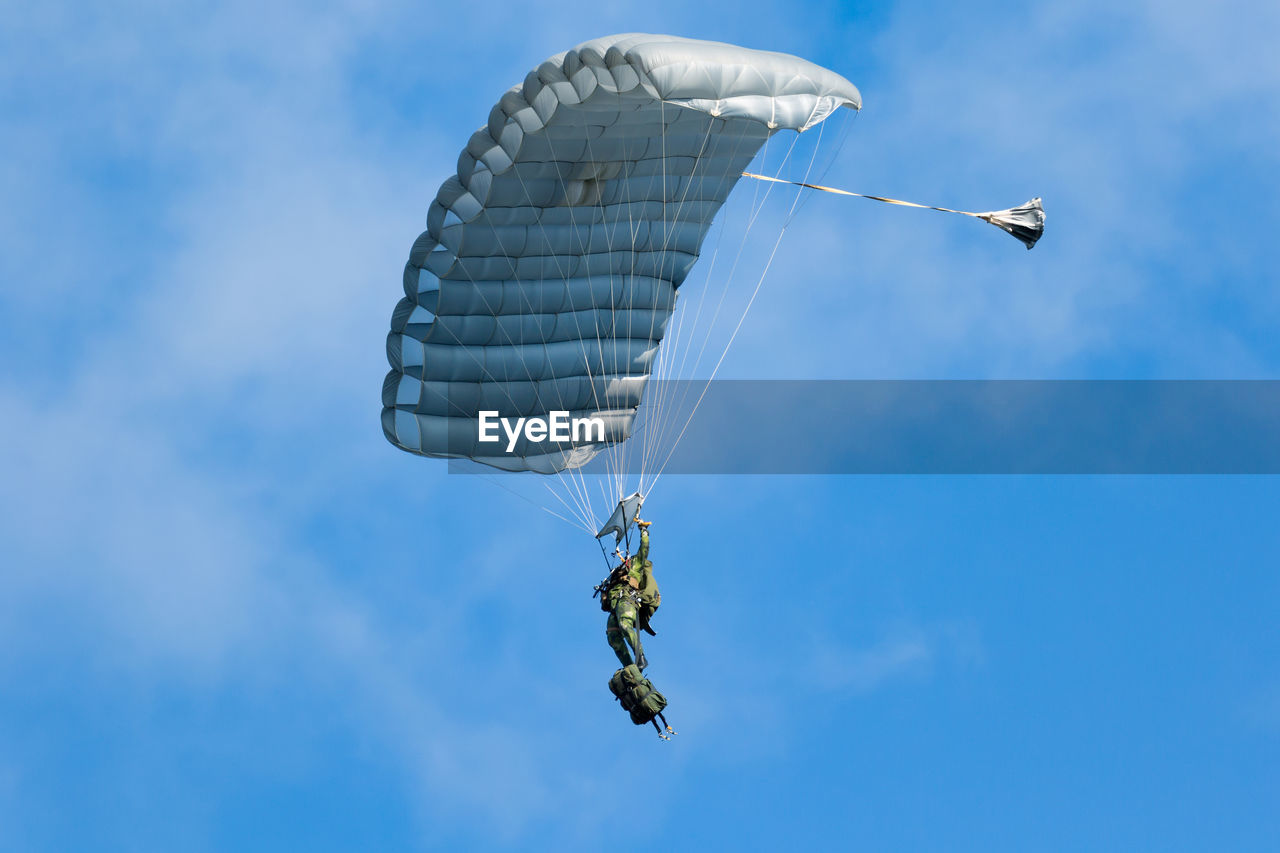 Low angle view of man paragliding against sky