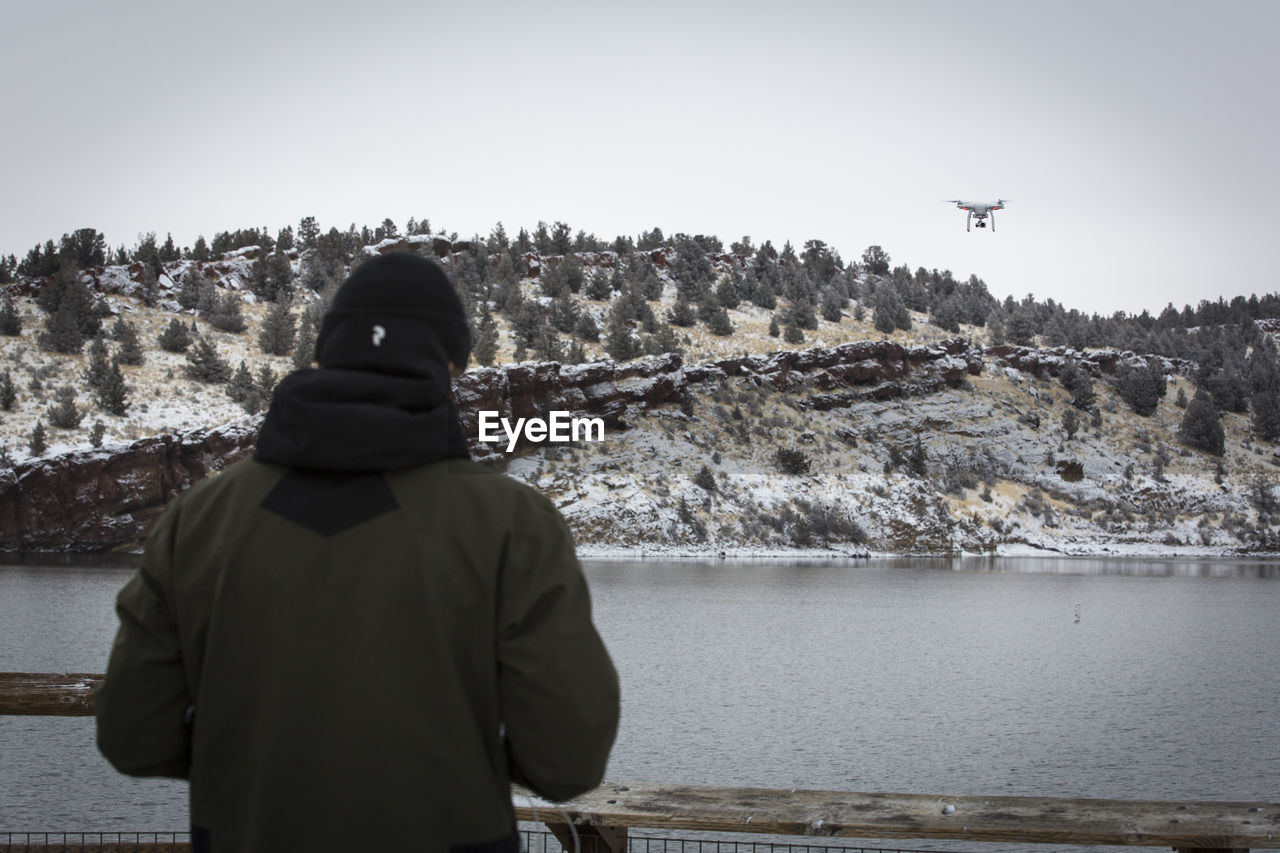 Young man flying drone above reservoir, oregon.