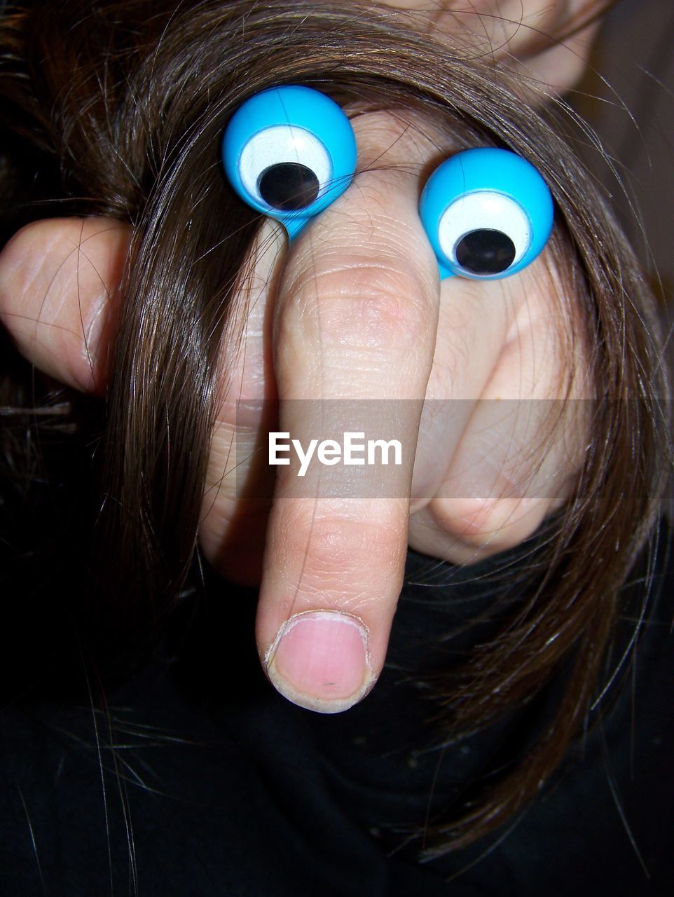Cropped image of hand with artificial eyes and hair