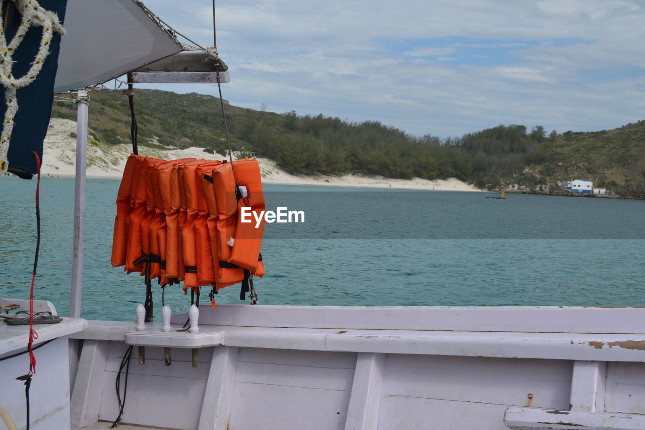 Lifebuoys drying on clothesline by sea against sky