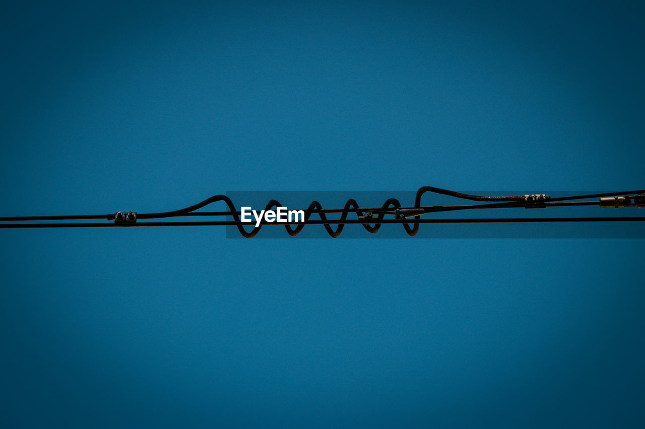 Low angle view of barbed wire against clear blue sky