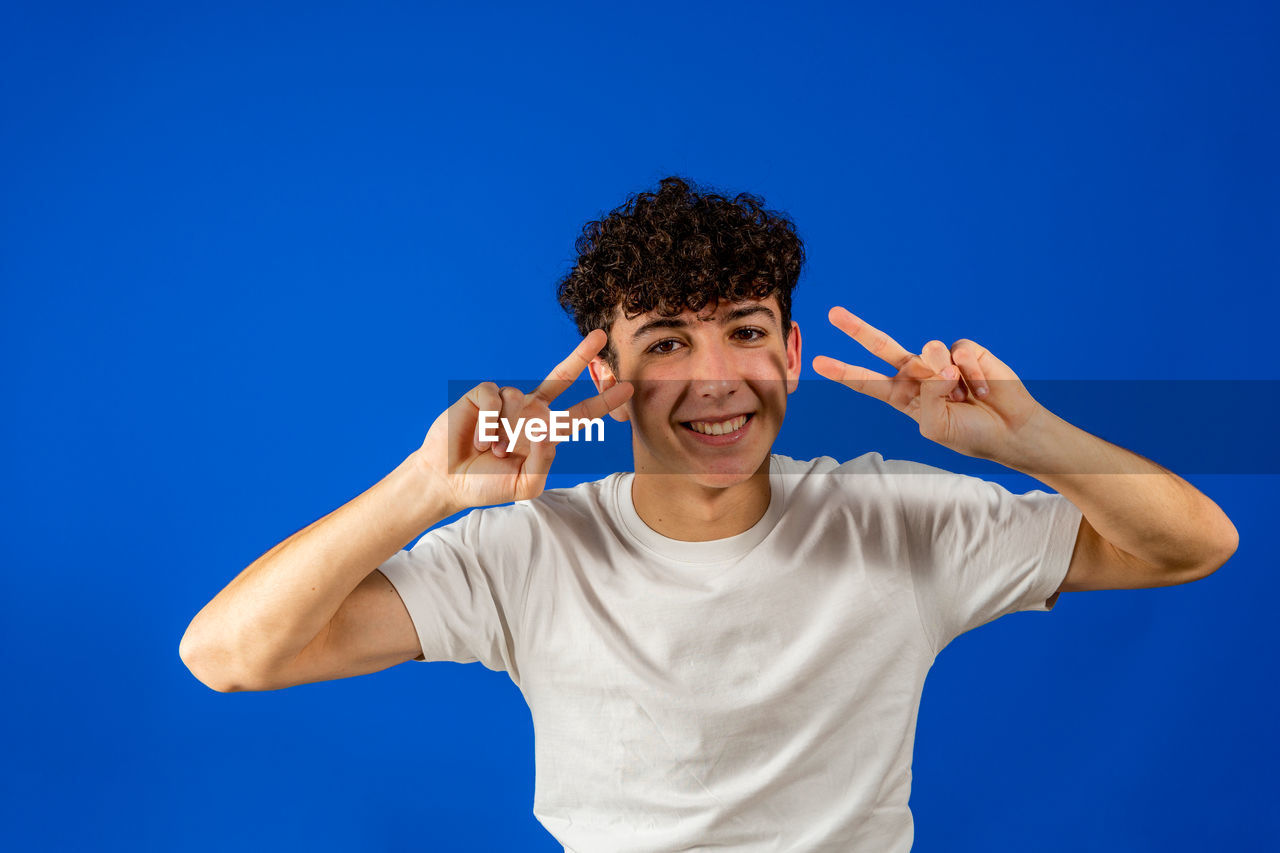 PORTRAIT OF A YOUNG MAN AGAINST BLUE BACKGROUND