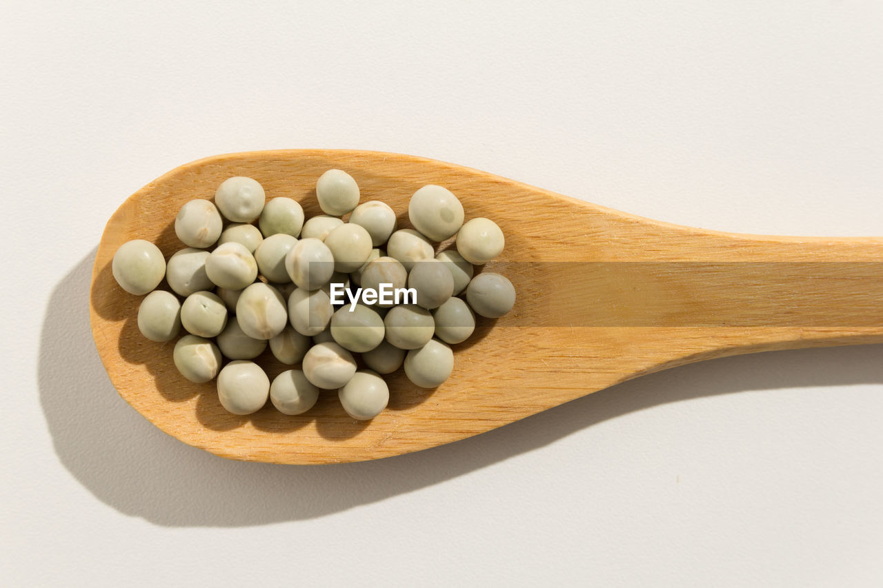 Close-up of beans in wooden spoon against white background
